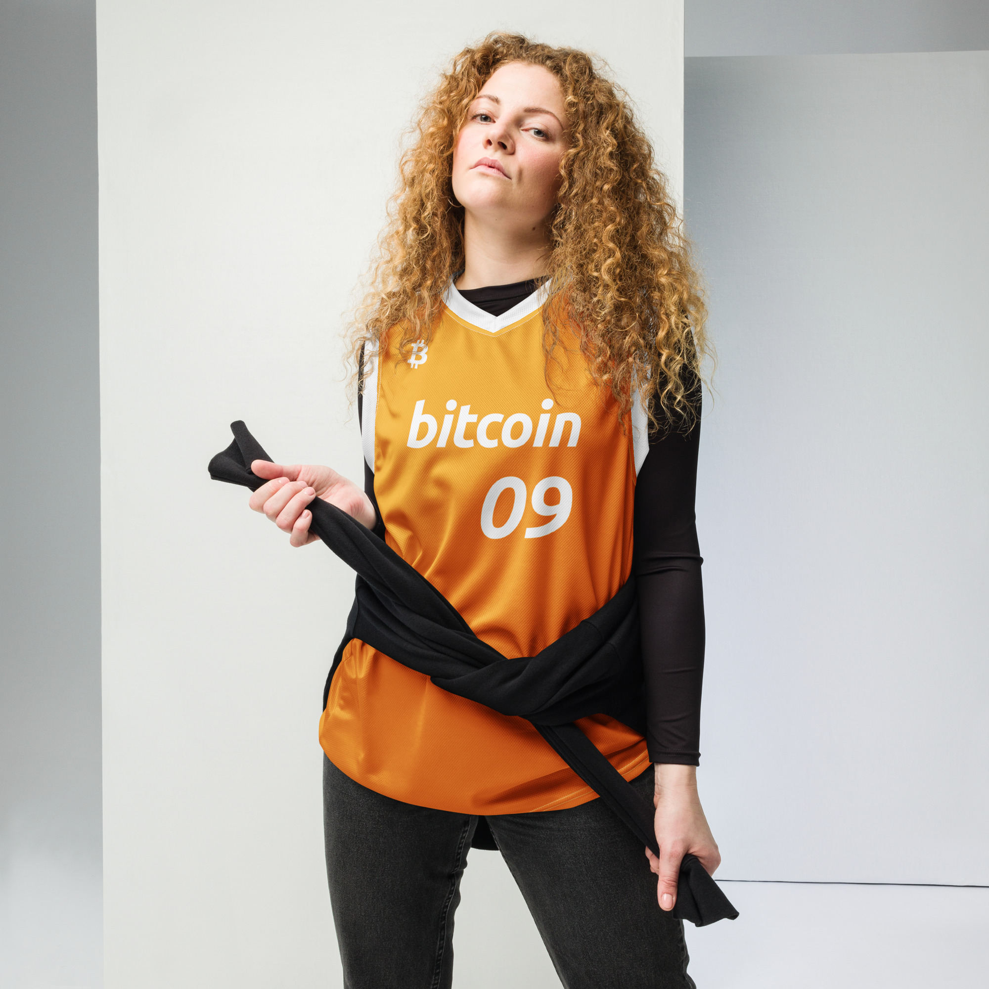 Front view of a Female wearing the Bitcoin Basketball Jersey with cargo pants. The Jersey features the Bitcoin icon in the top right chest, the Bitcoin logo and the number 09 to represent the year Bitcoin was created. The lettering is in bitcoin font Ubuntu bold italic.